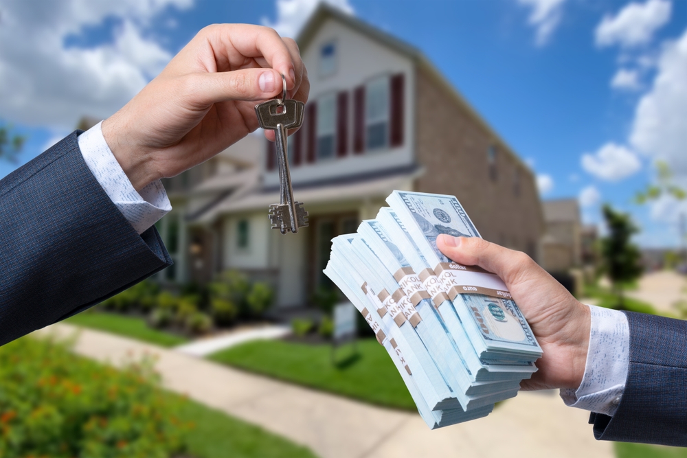 two men swapping keys and cash in front of a home